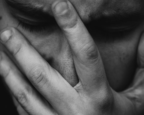 grayscale photo of person placing hand on face