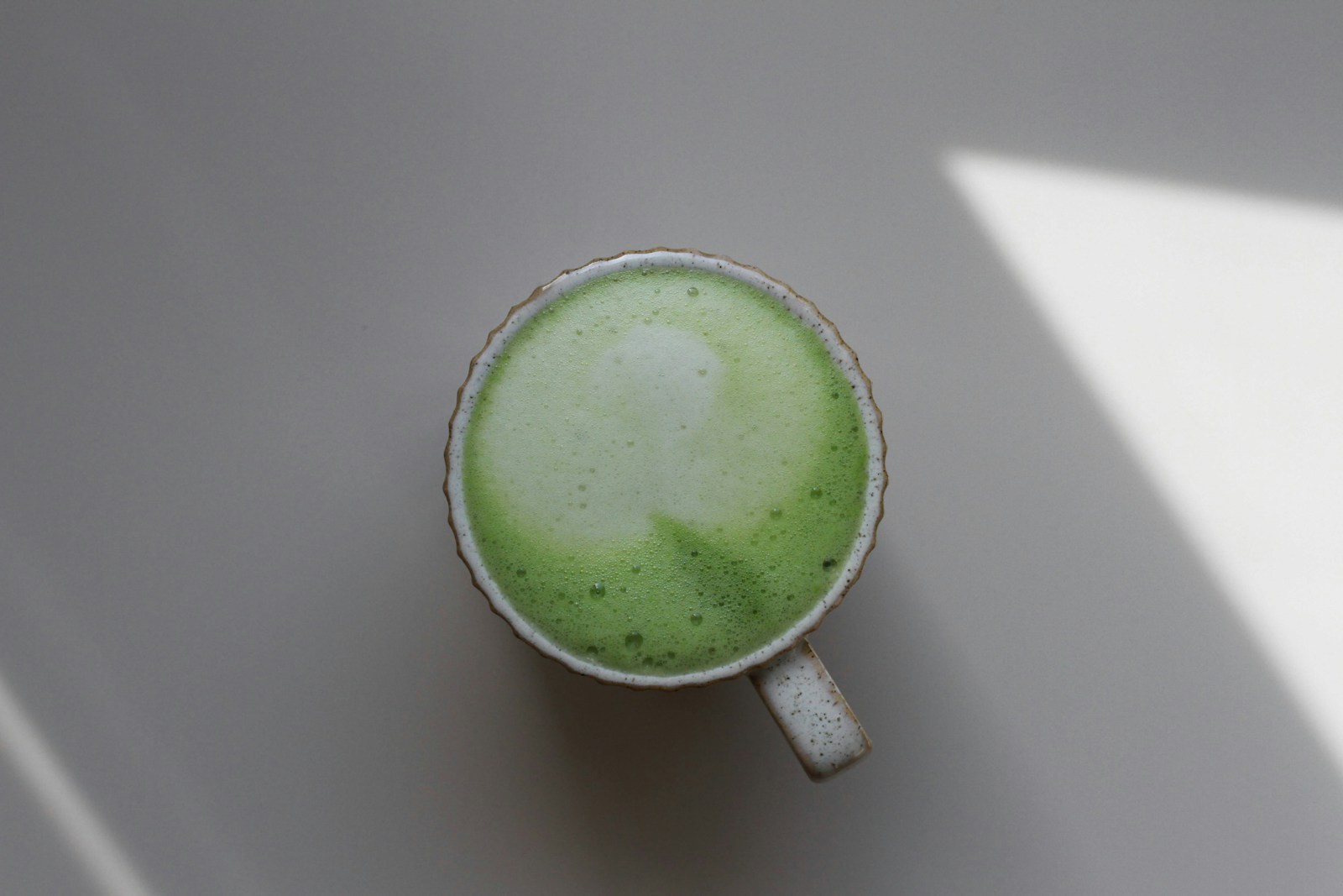 a cup of green liquid sitting on top of a table
