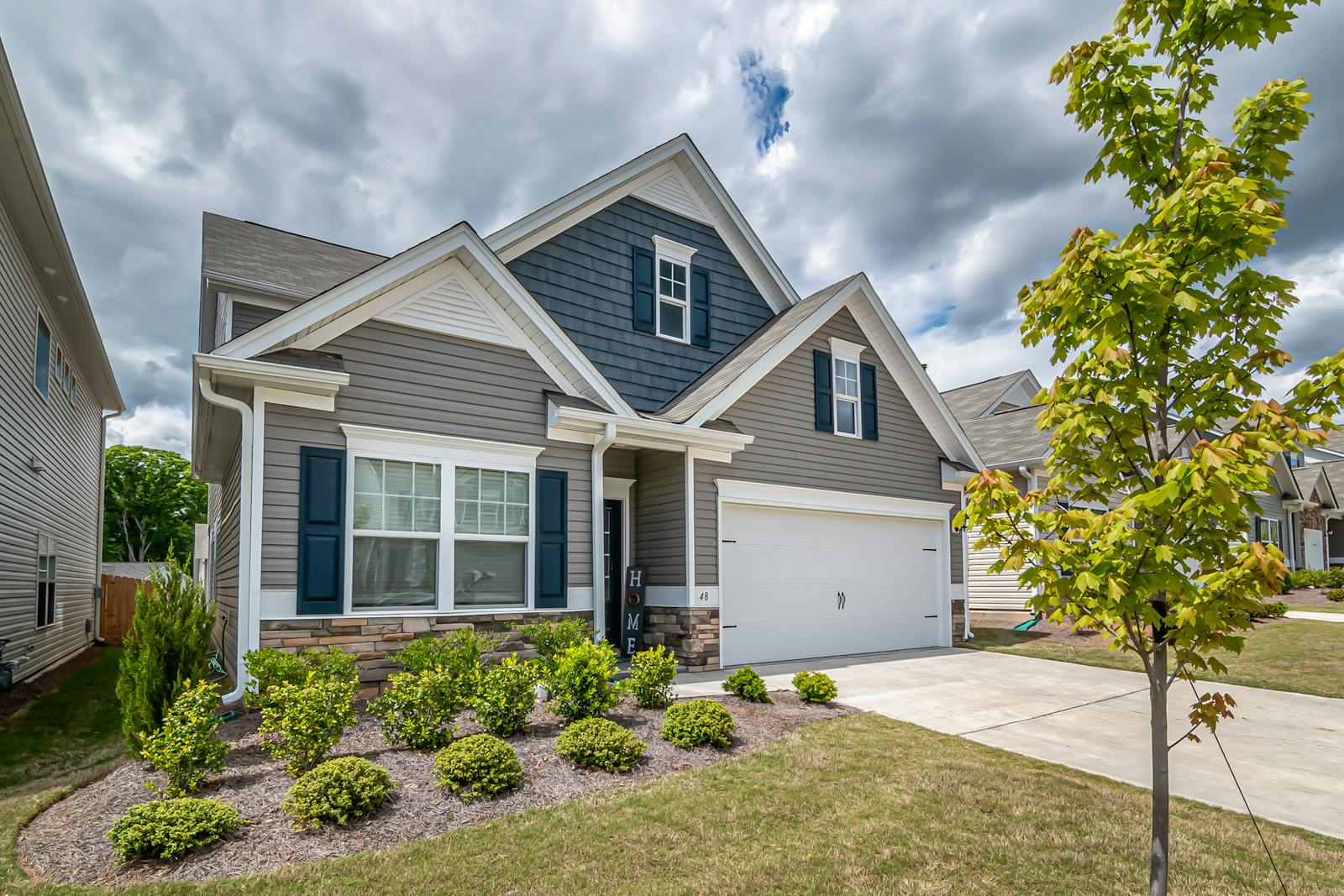 A beautiful suburban house with a manicured garden and cloudy sky, exemplifying modern architecture.