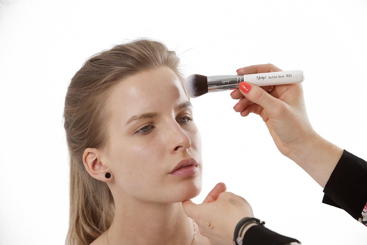 Vrouw die foundation aanbrengt met een make-up spons voor een spiegel