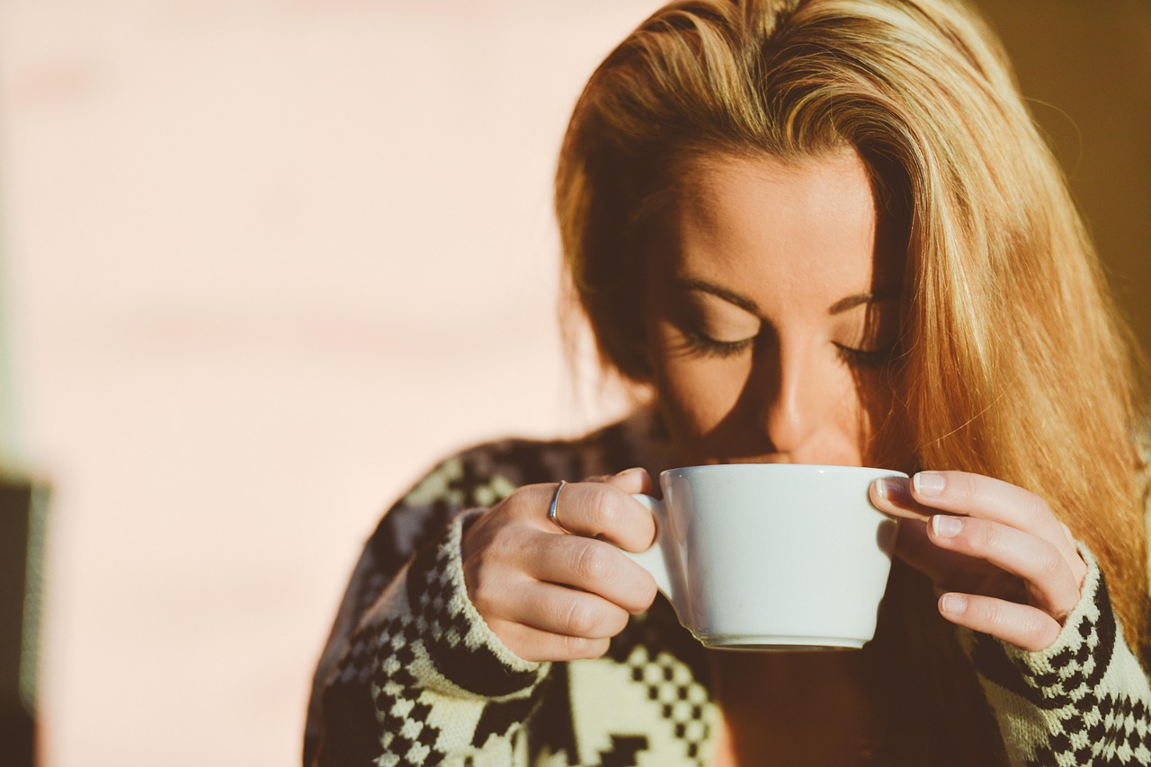 Vrouw die 's ochtends rustig koffie drinkt en schrijft in een journaal als onderdeel van haar dagelijkse zelfzorgroutine