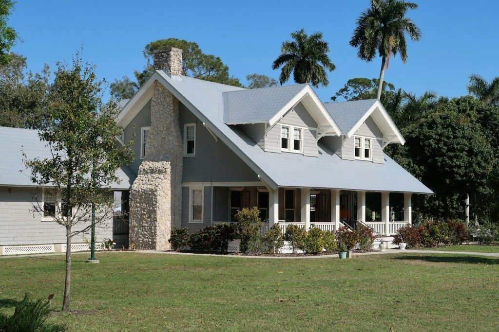 A grey house with a stone chimney and porch in Fort Myers, Florida