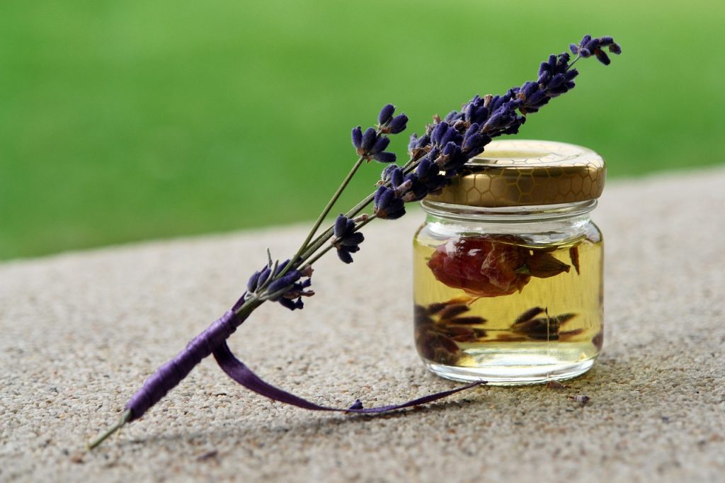 Flesje lavendelolie op een houten ondergrond naast gedroogde lavendelbloemen