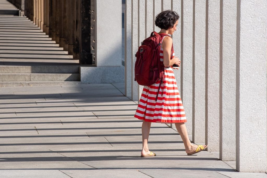 Petite vrouw in een stijlvolle gelaagde outfit met open jas en verticale lijnen die het silhouet verlengen
