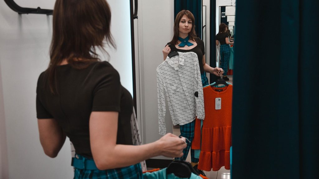 Vrouw past kleding in een paskamer en bekijkt de pasvorm in de spiegel