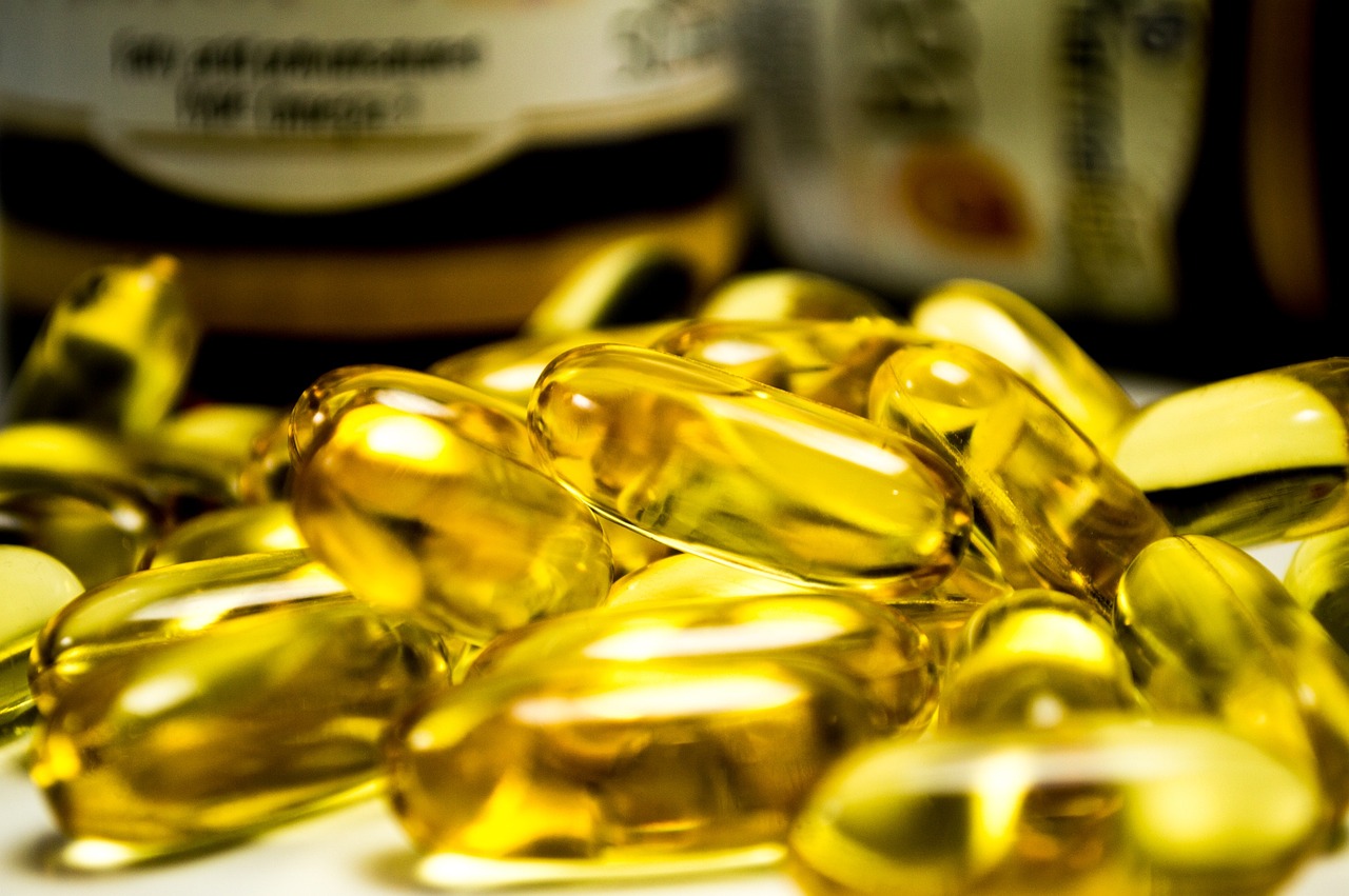Verschillende voedingssupplementen en vitaminepotjes op een houten tafel met herfstbladeren op de achtergrond